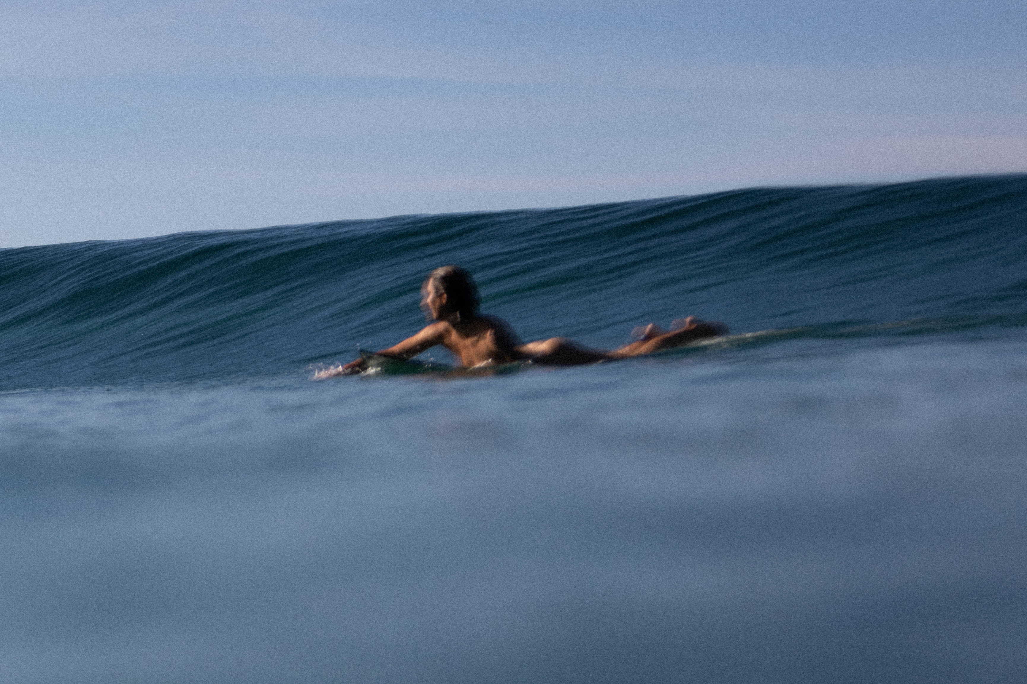 blurry photo of a female surfer about to catch a wave